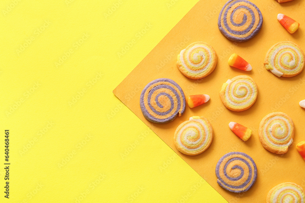 Different tasty cookies with candy corns for Halloween celebration on color background