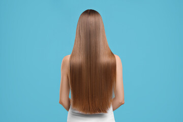 Wall Mural - Woman with healthy hair on light blue background, back view