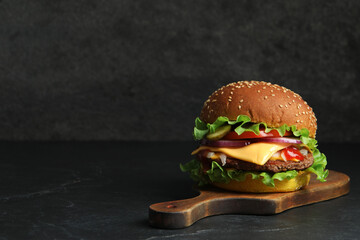 delicious burger with beef patty and lettuce on dark table, space for text