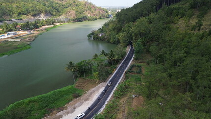 Aerial drone view Highway among mountains and trees and big river in Indonesia