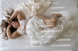 © ullision - top view of happy positive beautiful cheerful fat plump woman, with long hair relaxing in bed. Brunette cute chubby plus size girl enjoying morning sunlight stripes, body positivity