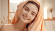 Woman in orange shower towel, showing moisturizing after shower. Cosmetics shot, advertising image for the beauty industry.