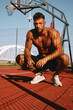 © djile - Shirtless handsome man rests after workout on a hot sunny day on the basketball court