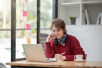 Wall Mural - Asian female student study online in class, study online, wearing headphones, watching video call, zooming, happy asian female learning language online with computer laptop.