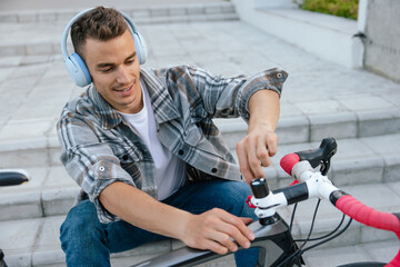 Young man repairing a bike while sitting on the steps