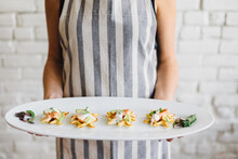 Server In Apron Holding Tray Of Hors D'oeuvres.