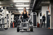 © Dusan Petkovic - Front view of a happy strong woman pushing weights in a gym during her strength training.