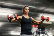 © dusanpetkovic1 - Low angle view of a muscular sportswoman lifting dumbbells in a gym.
