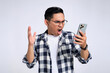 Upset young Asian man in casual shirt reading bad news on cell phone with angry face isolated on white background