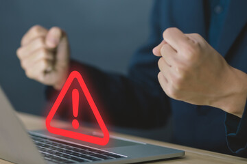 Wall Mural - businessman using laptop showing warning triangle and exclamation sign icon warning of dangerous pro