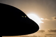 Silhouette of the front profile of a commercial aircraft against a orange setting sun