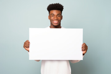 Happy young black man holding blank white banner sign, isolated studio portrait.