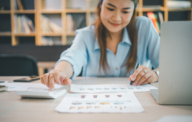 Wall Mural - Business asian woman sitting at a desk at an office By using the calculator to work. Business Concept Analysis and Planning.