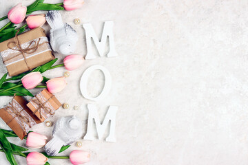 Wall Mural - Festive border from tulip flowers, gifts and birds with word MOM on light marble.