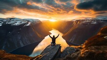 A Guy Is Sitting On The Edge Of The Cliff At The Top Of The Mountain That Sits Above Ringedalsvalnet, And He's Throwing His Hands Up In The Air As He Watches The Sun Go Down.