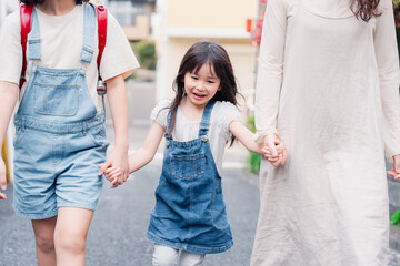 お母さんと手を繋いで学校に行く2人の女の子