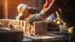 © sirisakboakaew - Closeup of bricklayer hands laying brick wall of house