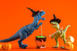 Two funny dinosaurs wearing witch hats are brewing potion in pot on  orange backgroun