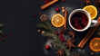 A cup of mulled wine or other warming drink with spices and a pine branch on a black background. Empty space for product placement or promotional text.