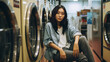 Young asian woman waiting in a laundry room