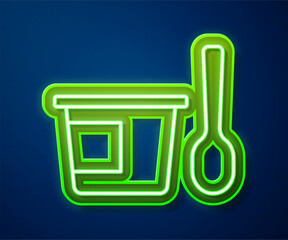 Sticker - Glowing neon line Yogurt container with spoon icon isolated on blue background. Yogurt in plastic cup. Vector