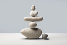 A Stone Zen Composition Captures The Essence Of Minimalistic Simplicity And Tranquility. Balanced Rock Stacks On A Gray And White Background. Concept Of Peace, Wellness, And Mindfulness. Copy Space