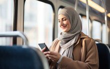 Smiling young muslim woman using smartphone on bus
