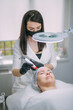 © Anna - Cosmetologist and dermatologist makes injections with a mesotherapy apparatus to a lying woman patient in a beauty salon.
