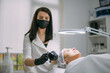 © Anna - Cosmetologist and dermatologist preparing for anti-aging injection for lying woman patient in beauty salon.