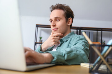 Male freelancer working with laptop at table in office, closeup