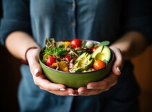 Woman's Hands Holding A Healthy Green Bowl Of Vegetables, Mushrooms, And Avocado
