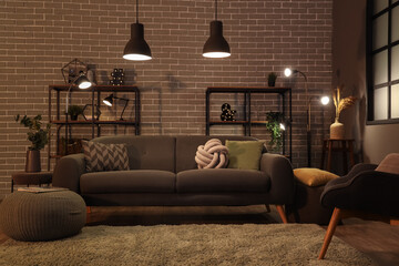 Interior of dark living room with cozy grey sofa and glowing lamps