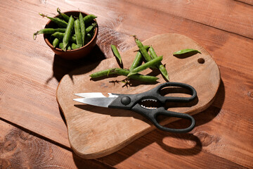 Canvas Print - New cutting board, scissors and bowl with green peas on wooden background