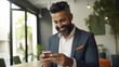 © B & G Media - A close-up of a smiling, mature businessman, either Latin or Indian, using a smartphone in his office for digital business solutions.