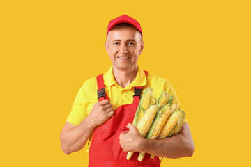 Canvas Print - Mature male farmer with ripe corn cobs on yellow background