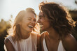© Odin AI - Two women laughing at each other outdoors