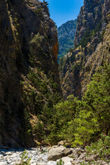 Canvas Print - Hikers in a deep gorge surrounded by spectacular cliffs during a hot summer