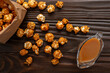 Caramelized popcorn in paper bag on wooden kitchen table flat lay