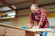 © contrastwerkstatt - Carpenter Sketching on a Wooden Beam in the Production Hall