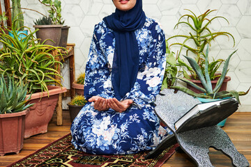 Wall Mural - Muslim woman praying and make douaa for Allah muslim god at room near home garden interior . Hands of muslim woman on the carpet praying