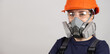 A woman wears a protective respirator with dust and gas filters on a white background.