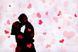 © Creativa Images - Silhouette of couple kissing with hearts background