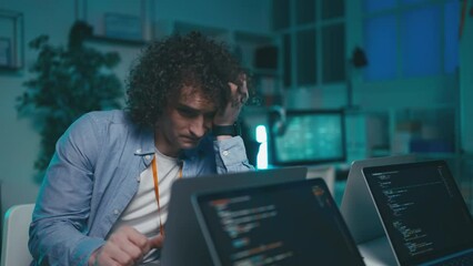 Exhausted young man working at night, tired IT engineer, developer occupation