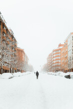 People Walking On Snowy Street Between Buildings