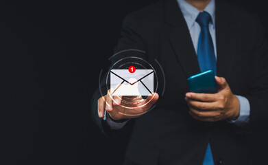 Wall Mural - businessman touching on a new email on a virtual screen while standing on a black background