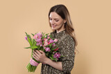 Fototapeta Tulipany - Happy young woman holding bouquet of beautiful tulips on beige background