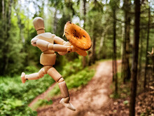 The Wooden Toy Mannequin In A Summer Or Autumn Forest With A Mushroom. The Concept Of Mushroom Picking, Nature Walk, Autumn Abundance
