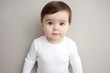 Product print template or mock-up for children's clothes: a caucasian baby wearing a white bodysuit or a t-shirt, smiling, standing in the studio on the white background