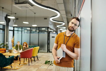 Wall Mural - upset bearded entrepreneur with documents and closed eyes, blurred coworkers talking in office