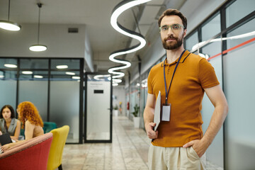 Wall Mural - bearded team lead with documents looking at camera near blurred businesswomen talking in office